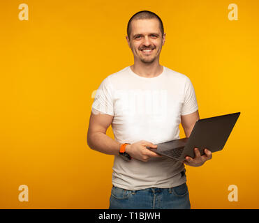 Freelancer man in white shirt holding laptop and smiling Stock Photo