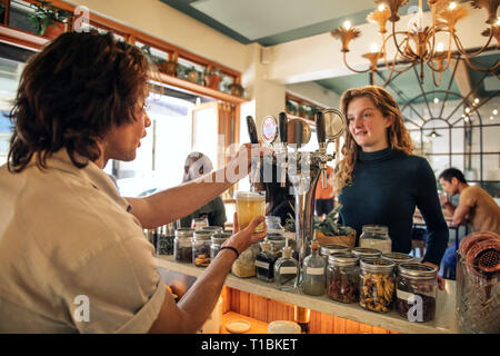 Smiling young woman ordering drinks in a pub Stock Photo