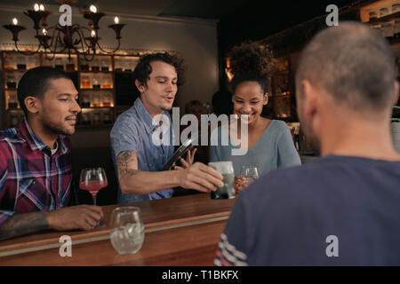 Smiling friends getting their drinks order in a bar Stock Photo