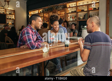 Smiling friends talking over drinks in a trendy bar Stock Photo