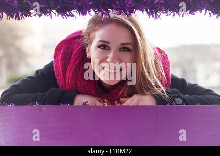 Portrait of smiling woman in winter back coat and pink scarf. Stock Photo