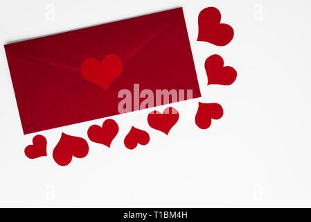 Concept of love letter in red envelope surrounded by romantic red hearts on white background. Copy space for Happy Valentines greetings. Mothers or Wo
