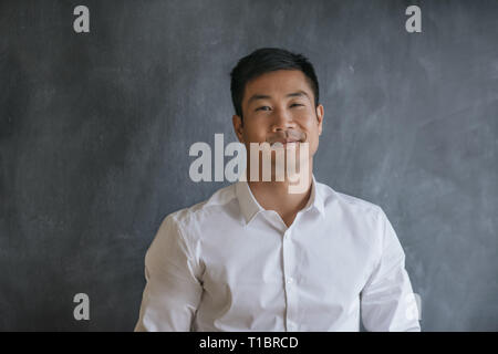 Asian businessman smiling while standing in front of a chalkboard Stock Photo