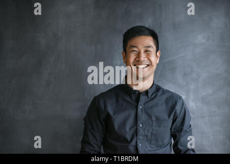 Smiling Asian businessman standing by a blank office chalkboard Stock Photo