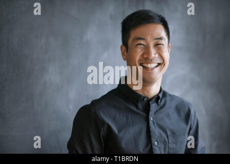 Smiling Asian businessman standing by a chalkboard in an office Stock Photo