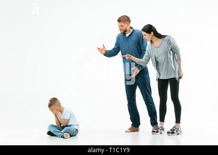 Angry parents scolding their son at home. Studio shot of emotional family. Human emotions, childhood, problems, conflict, domestic life, relationship concept Stock Photo