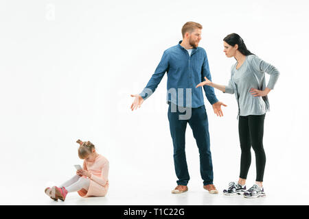 Angry parents scolding their daughter at home. Studio shot of emotional family. Human emotions, childhood, problems, conflict, domestic life, relationship concept Stock Photo