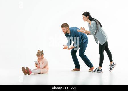 Angry parents scolding their daughter at home. Studio shot of emotional family. Human emotions, childhood, problems, conflict, domestic life, relationship concept Stock Photo