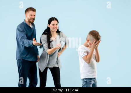 Angry parents scolding their son at home. Studio shot of emotional family. Human emotions, childhood, problems, conflict, domestic life, relationship concept Stock Photo