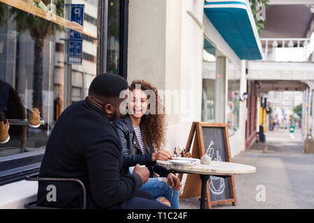 Two smiling friends talking together at a sidewalk cafe Stock Photo