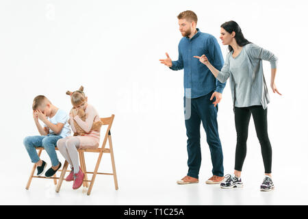 Angry parents scolding their children - son and daughter at home. Studio shot of emotional family. Human emotions, childhood, problems, conflict, domestic life, relationship concept Stock Photo