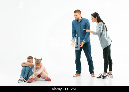 Angry parents scolding their children - son and daughter at home. Studio shot of emotional family. Human emotions, childhood, problems, conflict, domestic life, relationship concept Stock Photo