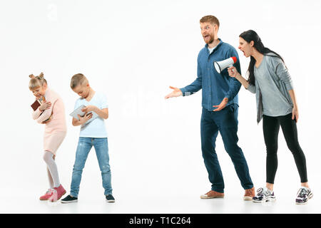 Angry parents scolding their children - son and daughter at home. Studio shot of emotional family. Human emotions, childhood, problems, conflict, domestic life, relationship concept Stock Photo