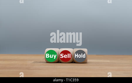 Symbol for the decision to buy, to sell or to hold. Three dice with the words 'Buy', 'Sell' and 'Hold'. Stock Photo