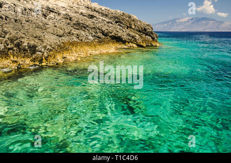 Summer view of crystal sea, with turquoise colorful water and rock coastline. Vacation trip by boat between blue caves in Greece. Stock Photo