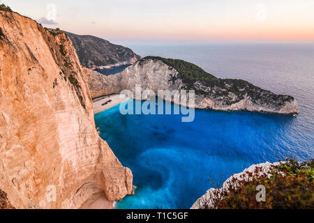 Famous landscape from the most beautiful beach - Navagio on Zakynthos island in Greece. Sunset view from the cliff edge on blue sea and picturesque se Stock Photo
