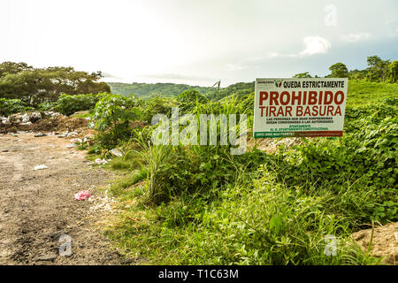 Contrast of a roadside dumping ground next to government sign saying 'No dumping' Stock Photo