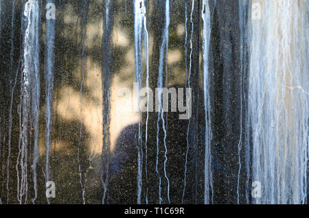 Black Polished Granite Wall with White Outgrowths Leaking from the Weather. Streaks on the Wall Stock Photo