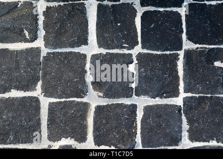 Black Granite Cobblestone Texture with White Seams. Black Chopped Cobbles Background. Stock Photo