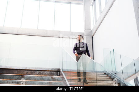 A young businessman walking down the stairs in office building. Stock Photo
