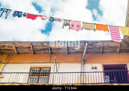 Linen is Dried on Clothesline on a Background of Blue Sky with Clouds. Sunny day in the Yard-Well. Old Building Facade Stock Photo