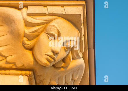 Stucco Sculpture of a Female Mask with Wings as a Decorative Element of the Building Against Blue Sky at Sunset Stock Photo