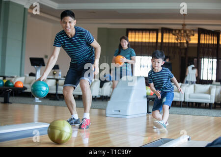 Father teaching son and family play bowling at bowling club on relax time Stock Photo