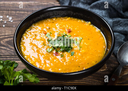 Red lentil soup in black bowl. Stock Photo