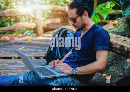 Asian man working and checking photo on laptop at outdoor nature and He is relaxing, enjoying on travel Stock Photo
