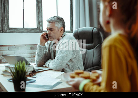 Serious mature man putting a phone to his ear Stock Photo