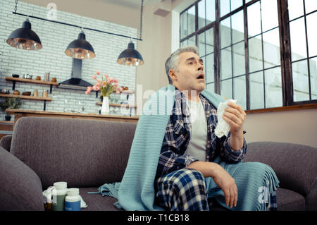Gloomy ill man being ready to sneeze Stock Photo