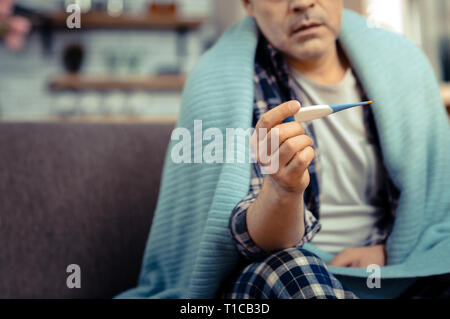 Selective focus of a thermometer in male hand Stock Photo