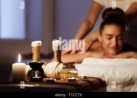 Woman relaxing in spa salon with herbal bags on wooden tray Stock Photo