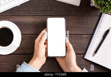 Woman using blank smartphone on workplace desk Stock Photo