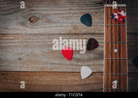 Acoustic guitar fretboard and some guitar picks on wooden table Stock Photo