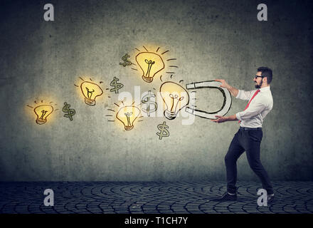 Business man attracts bright ideas light bulbs with a big magnet Stock Photo