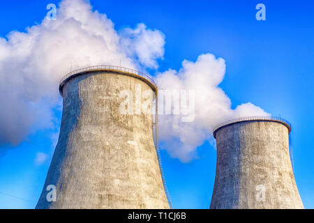 Two big smoking pipes of powerplant. Heavy white smoke on blue sky background. Stock Photo