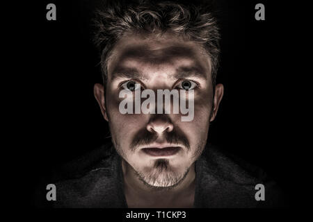 Portrait of serious young man Isolated on black background Stock Photo