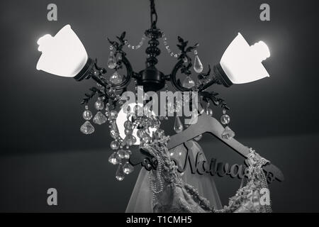 Wedding dress hanging on a hanger. Decorated hanger in portuguese -Fashion look. Interior of bridal salon - Back and Grey - Image Stock Photo