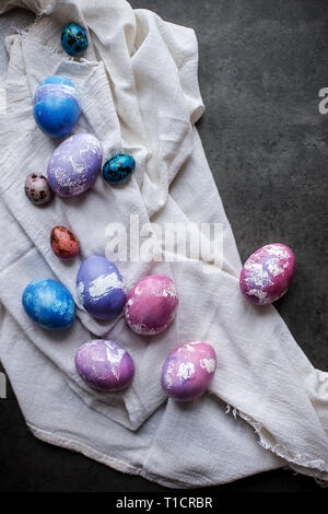 Composition of Colorful Easter chicken eggs with white napkin on dark background. Concept of Easter painted eggs Stock Photo