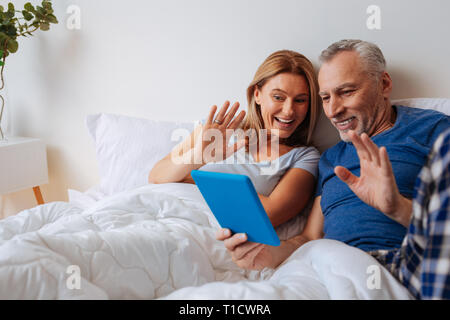 Loving parents waving their hands while having video chat with son Stock Photo