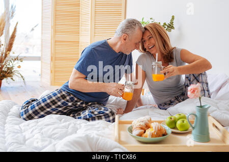 Husband touching forehead of wife having breakfast together Stock Photo