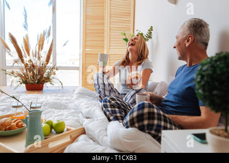 Couple having much fun while having breakfast in bedroom Stock Photo