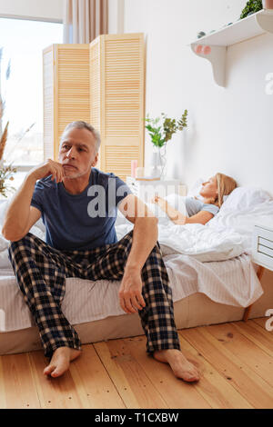 Businessman sitting on bed feeling overloaded with thoughts