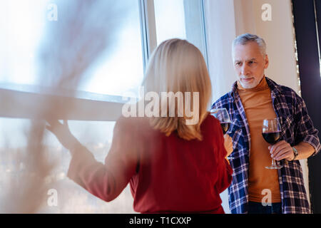 Businessmen standing near window at home and drinking red wine Stock Photo