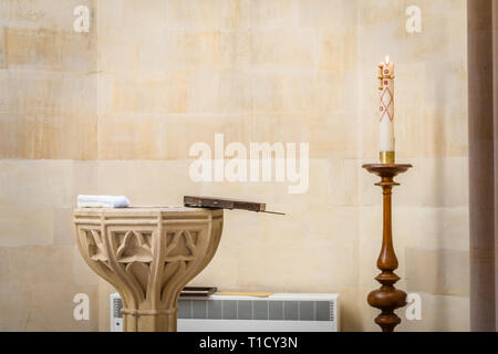 Opened baptismal font and a lit church candle prior to a Christening taking place inside Arundel Cathedral, West Sussex, England, UK Stock Photo