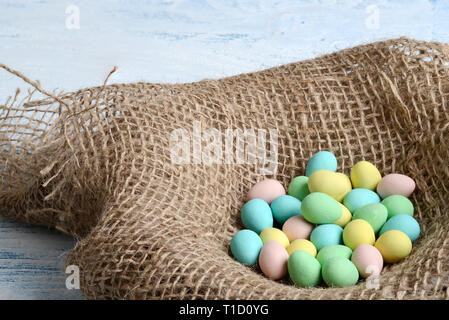Closeup burlap bird nest with easter candy eggs Stock Photo