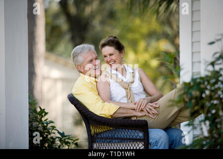 Mature adult woman sitting on her husbands knee. Stock Photo