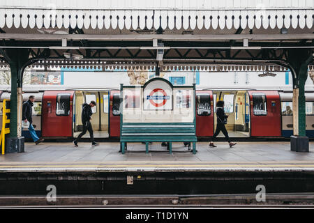 London, UK - March 16, 2019: People walking past the station name sign on the outdoor platform of Golders Green tube station. London Underground is th Stock Photo