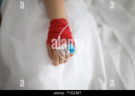 Details with a cannula on the hand of a ill little girl in a pediatric hospital reserve Stock Photo